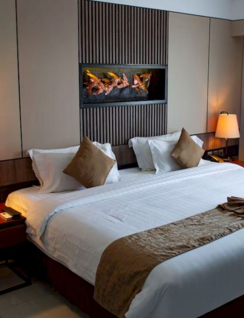 A neatly made hotel room with a king-sized bed, decorative pillows, bedside lamps, and warm lighting in a modern setting.