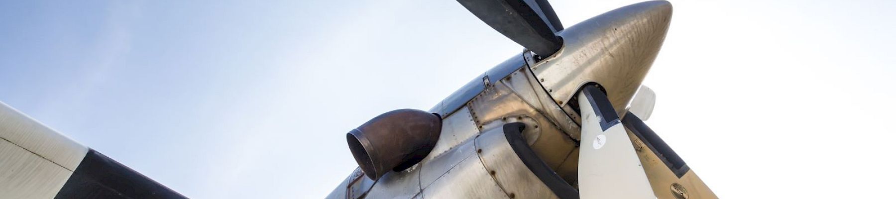 The image shows a close-up of a propeller on an aircraft, with four blades against a clear sky background.